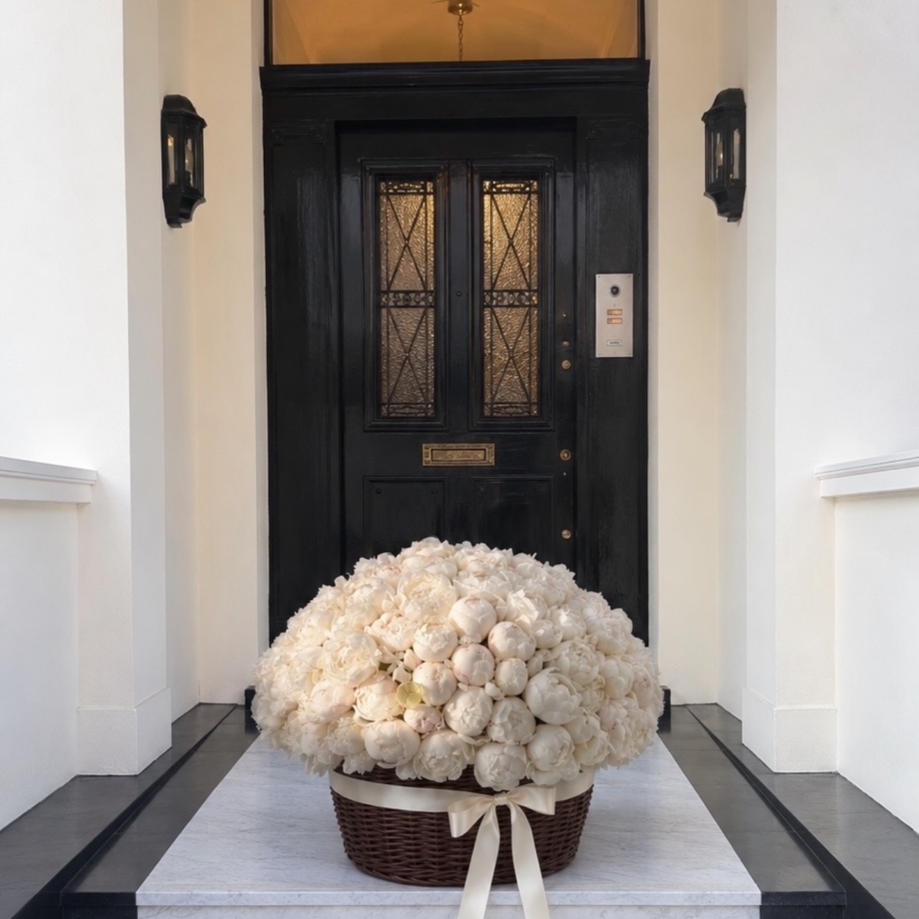 White peonies in a basket on a marble doorstep